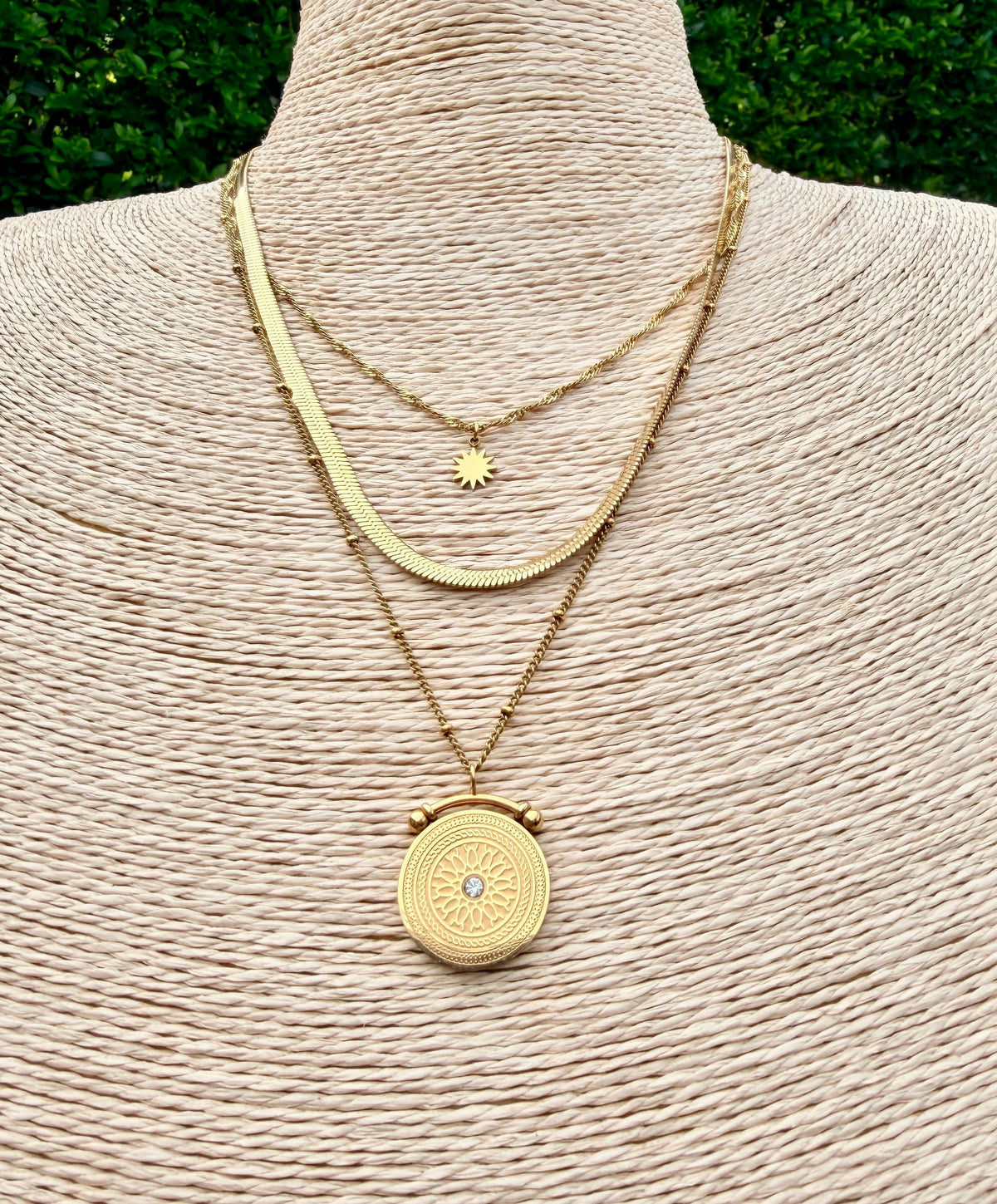 An image of 3 gold necklaces stacked on a bust.