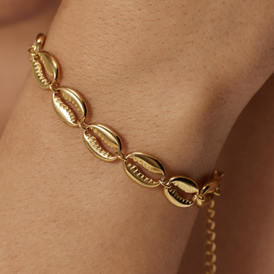 Gold bracelet on a wrist with a neutral background